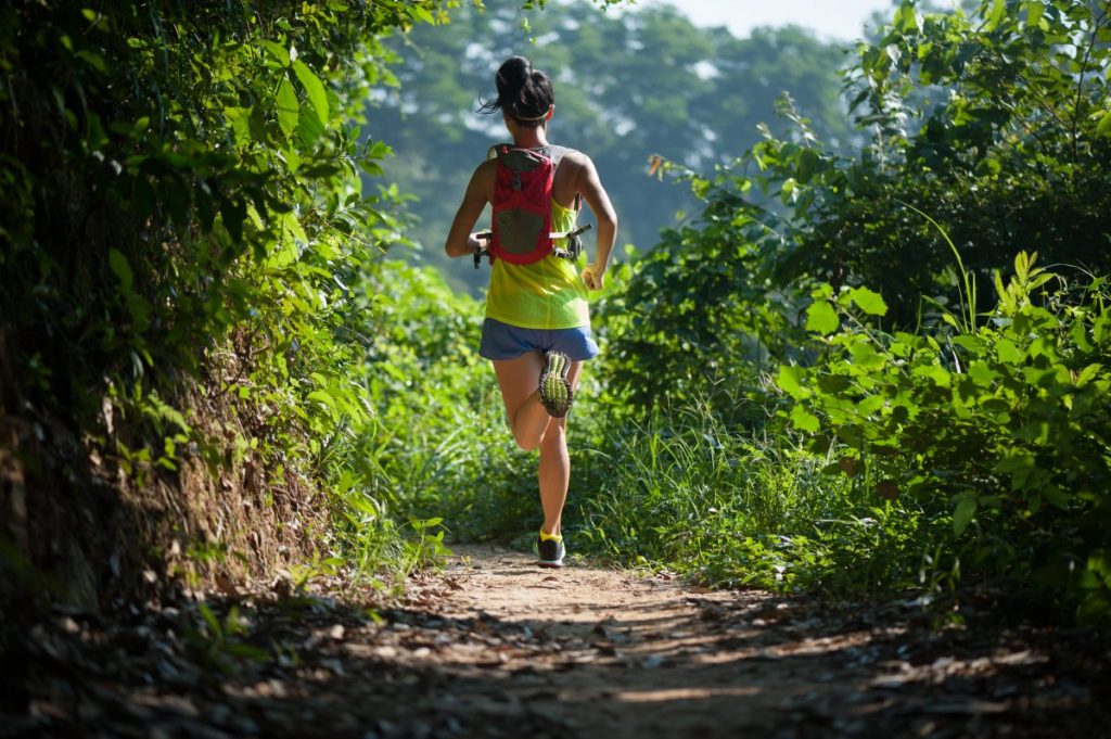 Woman running through woods.